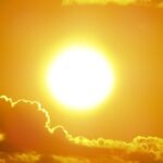 A stunning view of the golden sun shining through clouds at sunset, casting a warm glow.