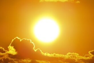 A stunning view of the golden sun shining through clouds at sunset, casting a warm glow.