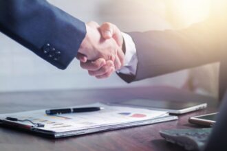 Professional handshake agreement over business charts in an office setting.